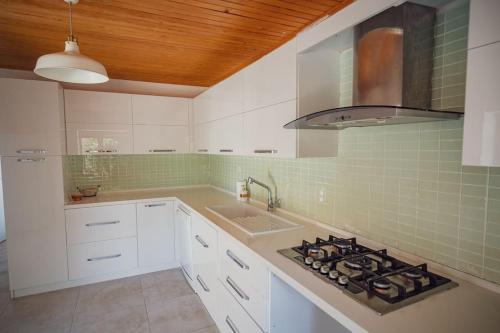 Una cocina blanca con estufa y fregadero. en Urla Sunrise House, en Ildir