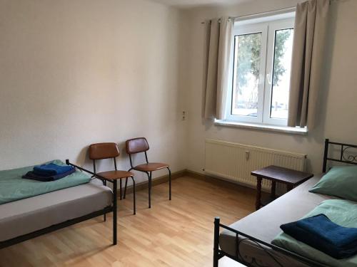 a room with two beds and two chairs and a window at Ferienwohnung Monteurzimmer Haus Arnstadt in Arnstadt