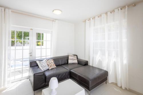 a living room with a black leather couch in front of a window at Artiko Luxury Suites - Jan Thiel in Jan Thiel