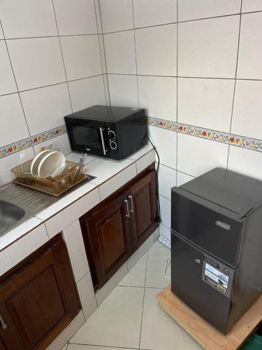 kuchnia z kuchenką mikrofalową na blacie obok zlewu w obiekcie Henock résidence w mieście Abidżan