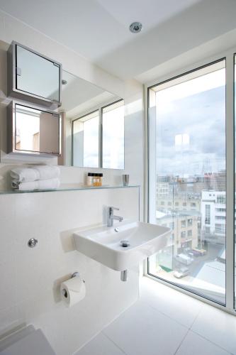 a white bathroom with a sink and a window at The Rosebery by Supercity Aparthotels in London