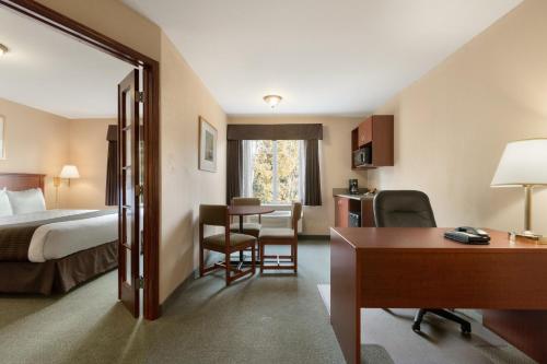 a hotel room with a bed and a desk and a table at Days Inn by Wyndham Thunder Bay North in Thunder Bay