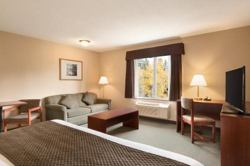 a hotel room with a bed and a couch and a television at Days Inn by Wyndham Thunder Bay North in Thunder Bay