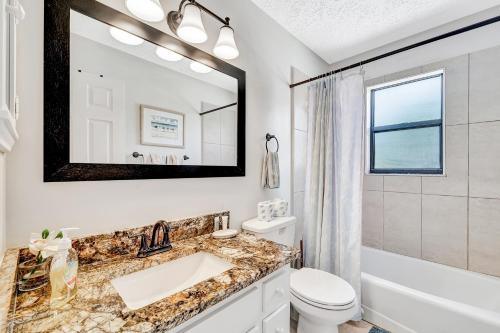 ein Badezimmer mit Waschbecken, Toilette und Spiegel in der Unterkunft Blissful Beach Retreat Super in Englewood