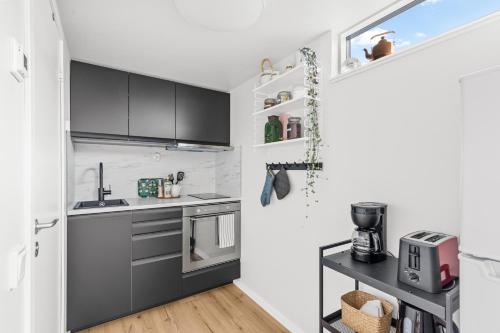 a kitchen with gray cabinets and a sink at Gäststuga i historiska Gamla Uppsala in Uppsala