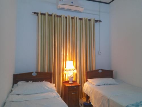 a bedroom with two beds and a lamp on a table at Blessing Home in Badalgama