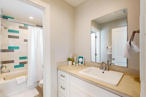 ein Badezimmer mit Waschbecken, Badewanne und Spiegel in der Unterkunft Mercer Village at Old Town #3B in Port Aransas