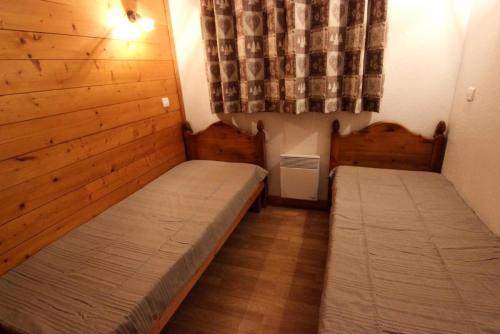- 2 lits dans une petite chambre avec des murs en bois dans l'établissement Résidence Bouquetin - 3 Pièces pour 6 Personnes 48, à Val Thorens
