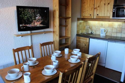 - une table en bois avec des tasses et de la vaisselle dans la cuisine dans l'établissement Résidence Eterlous - ETERLOUS APPARTEMENT 35M² 6P BELLE VUE CENTRE STATION 59, à Val Thorens