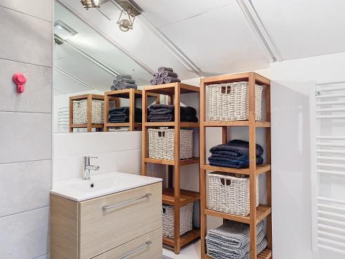 La salle de bains est pourvue d'un lavabo et d'étagères avec des serviettes. dans l'établissement La Terrasse - Charmante Maison, à Cholet