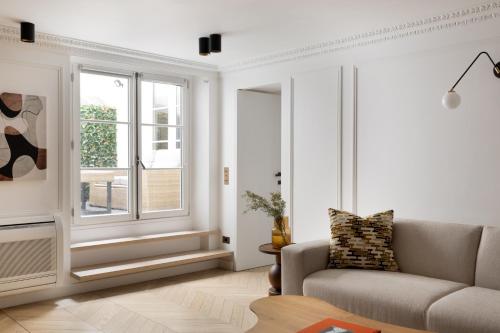 un salon avec un canapé et une fenêtre dans l'établissement HIGHSTAY - Luxury Serviced Apartments - Saint-Honoré, à Paris
