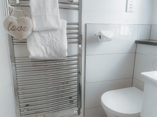 a bathroom with a toilet and towels on a rack at Cotswold Dream Getaways in Cirencester