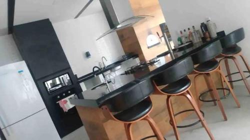 a kitchen with a bar with stools and a sink at Condomínio Blue: O Paraíso que Você Merece! in Xangri-lá