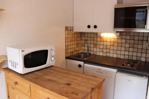 - un four micro-ondes installé au-dessus d'un comptoir en bois dans la cuisine dans l'établissement Résidence Lac Du Lou - VAL THORENS STUDIO 4 PERSONNES AVEC BELLE VUE ET ACCES DIRECT AUX PISTES MAE-7557, à Val Thorens