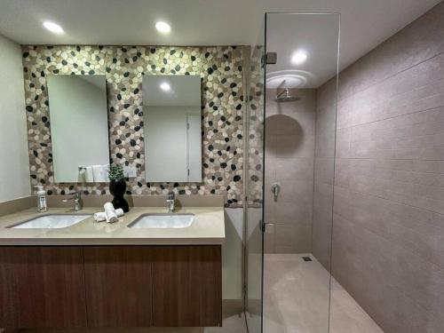 a bathroom with two sinks and a glass shower at Ocean Front, Luxurious Condo in Downtown Jaco! in Jacó