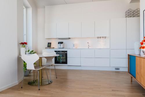 a kitchen with white cabinets and a table and chairs at View from the 18th floor over whole of Copenhagen. in Copenhagen