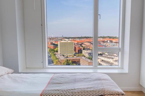 a bedroom with a large window overlooking a city at View from the 18th floor over whole of Copenhagen. in Copenhagen
