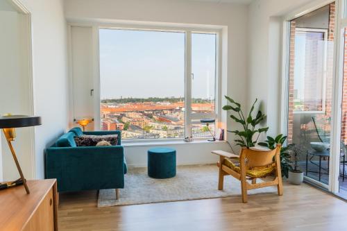 a living room with a blue couch and a large window at View from the 18th floor over whole of Copenhagen. in Copenhagen