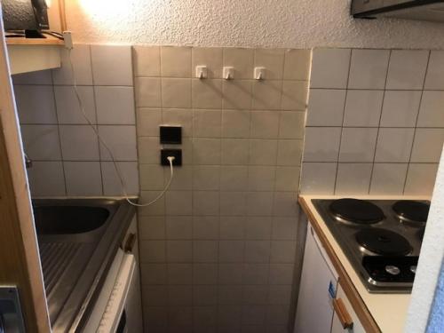 - une cuisine carrelée de blanc avec évier et cuisinière dans l'établissement Résidence Eskival - 2 Pièces pour 4 Personnes 92, à Val Thorens