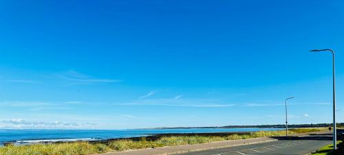 a road with a street light next to a body of water at Sea View in Port Seton