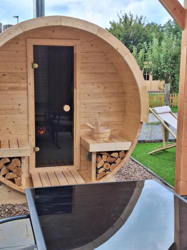 a circular wooden sauna with a grill in a yard at 'Relax Lodge Sea' - Wellness lodge in Zeeland - Private Sauna - Airco - Garden - Outdoor Swimming pool - Free Wifi, Towels & Bed linen in Heinkensand