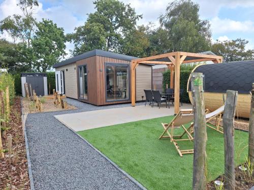 a tiny house in a garden with a gazebo at 'Relax Lodge Sea' - Wellness lodge in Zeeland - Private Sauna - Airco - Garden - Outdoor Swimming pool - Free Wifi, Towels & Bed linen in Heinkensand