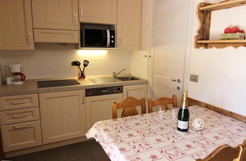 - une cuisine avec une table et une bouteille de vin dans l'établissement Résidence Altineige - ALTINEIGE STUDIO CABINE 25M² 4 PERS STYLE CHALET MAE-7682, à Val Thorens
