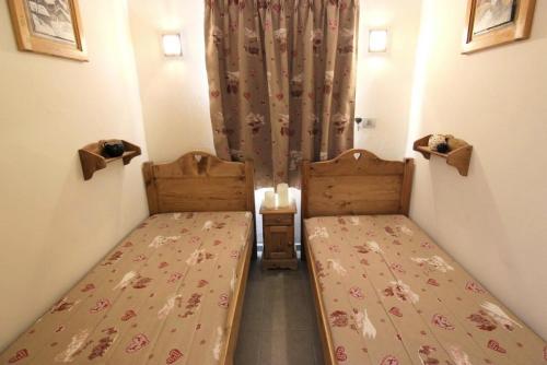 Cette petite chambre comprend 2 lits et un rideau. dans l'établissement Résidence Altineige - ALTINEIGE STUDIO CABINE 25M² 4 PERS STYLE CHALET MAE-7682, à Val Thorens