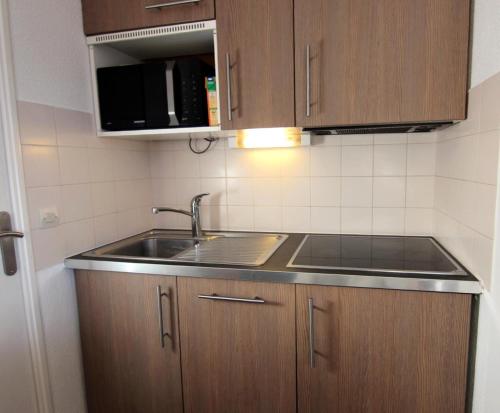 une cuisine avec un évier et des armoires en bois dans l'établissement Résidence Reine Blanche - APPARTEMENT CHARMANT ET BIEN EQUIPE POUR 4 PERSONNES ENTREE DE STATION MAE-7702, à Val Thorens
