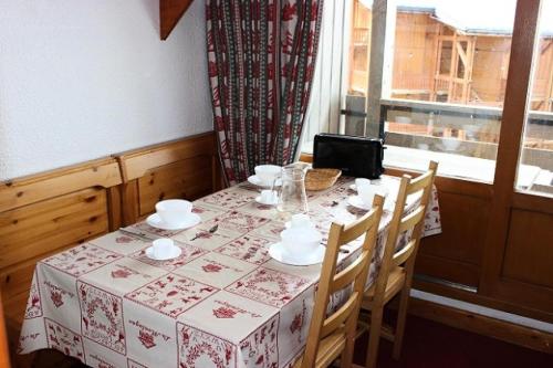 une table avec un tissu de table, des chaises et une fenêtre dans l'établissement Résidence Orciere - VAL THORENS AGREABLE 2 PIECES POUR 4 PERSONNES ORIENTE SUD ET PIED DES PISTES MAE-7698, à Val Thorens