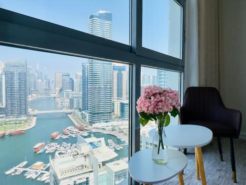 a vase of pink flowers on a table in front of a window at Elite Waterfront 3BR Haven - Marina and Sea Views! in Dubai