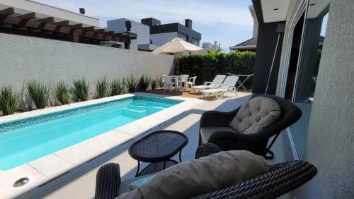 un patio avec des chaises et une piscine dans l'établissement Verão Relaxante no Condomínio Las Palmas, à Xangri-lá