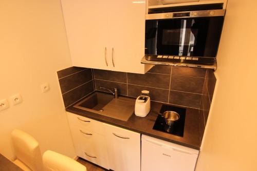 une petite cuisine avec un évier et un micro-ondes dans l'établissement Résidence Hauts De Chaviere - HAUTS DE CHAVIERE STUDIO 23M² 4PERS PLACE SLALOM DECO MODERNE MAE-7756, à Val Thorens