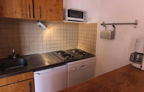 une petite cuisine avec une cuisinière et un micro-ondes dans l'établissement Résidence Trois Vallees - STUDIO 3 PERSONNES A 2 PAS DU CENTRE QUARTIER PECLET MAE-7761, à Val Thorens