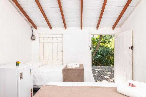 a bedroom with two beds and a window at Pousada da Praça Caraíva in Caraíva