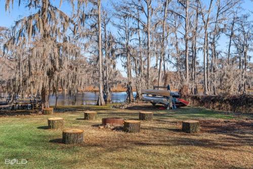 a park with a bench and trees and a lake at Cedar Wood Lodge Wkayaks & Canoes, Outdoor Dining in Karnack