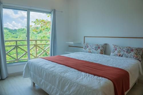 Un dormitorio con una cama y una ventana grande. en Saman Residence, en Las Terrenas