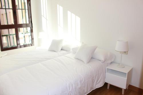 a white bed in a room with a window at Apartaments Plaza Príncipe Viana in Pamplona