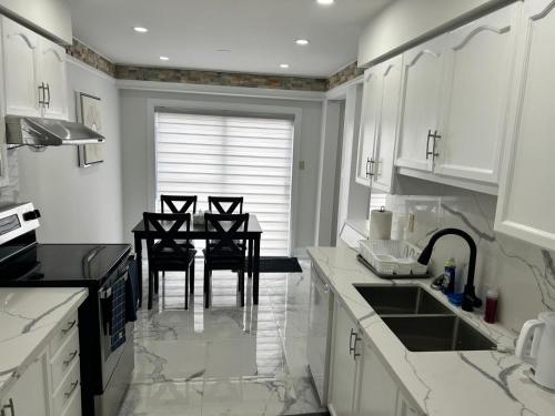 a kitchen with white cabinets and a table with chairs at Treasure Haven Near Tourism Barrie in Barrie