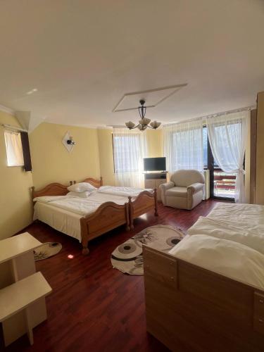 a bedroom with two beds and a couch and a chair at Vila Alunis in Buşteni