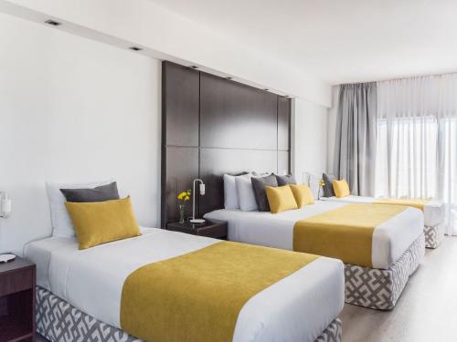 two beds in a hotel room with yellow and white at HTL City Baires in Buenos Aires
