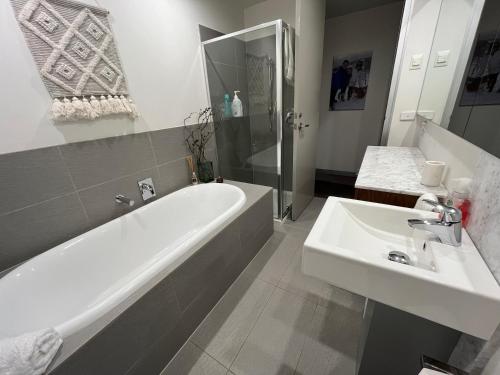 Un baño con bañera blanca y lavabo. en Woodsmoke Seven, en Falls Creek