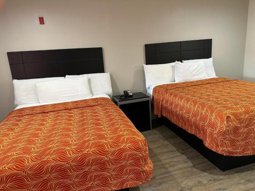 a hotel room with two beds and a night stand at Palace Inn I-45 & Bellfort in Houston