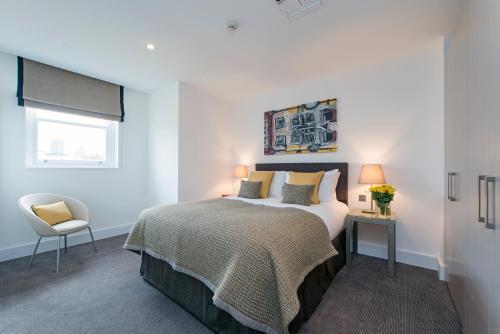 a bedroom with a bed and a chair and a window at The Rosebery by Supercity Aparthotels in London