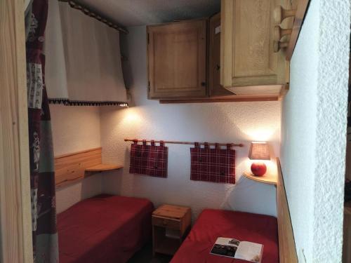 Cette petite chambre comprend 2 lits rouges et des armoires. dans l'établissement Résidence Cimes De Caron - CIMES DE CARON STUDIO CABINE 24M² 4 PERS MAE-1864, à Val Thorens