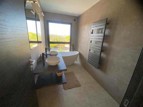 une salle de bain avec une baignoire, un lavabo et une fenêtre dans l'établissement Plage de la Nartelle Maison vue mer, à Sainte-Maxime