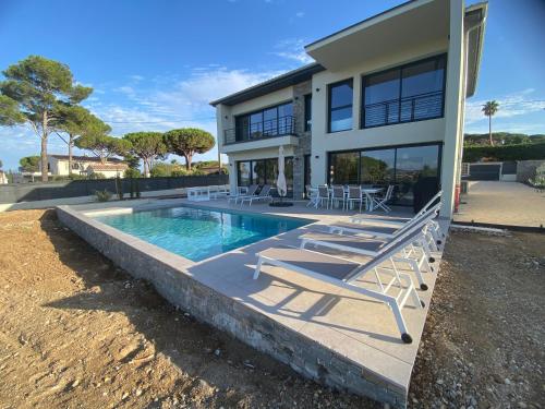 une maison avec une piscine et des chaises en face de celle-ci dans l'établissement Plage de la Nartelle Maison vue mer, à Sainte-Maxime