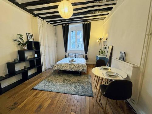 une chambre avec un lit, une table et une fenêtre dans l'établissement Charmant Appartement Parisien Près du Louvre Paris, France, à Paris