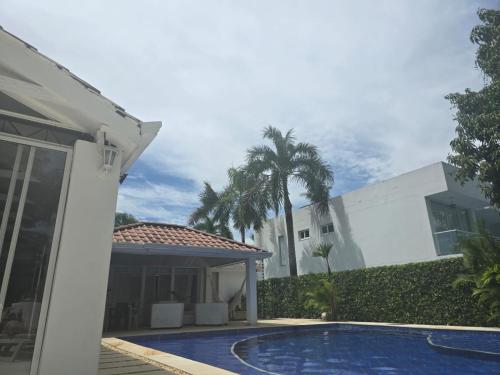 a villa with a swimming pool in front of a house at Hermosa casa en condominio campestre el peñon in Girardot