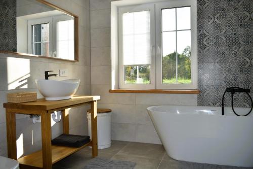 a bathroom with a tub and a sink and two windows at Villa Asta in Rusnė